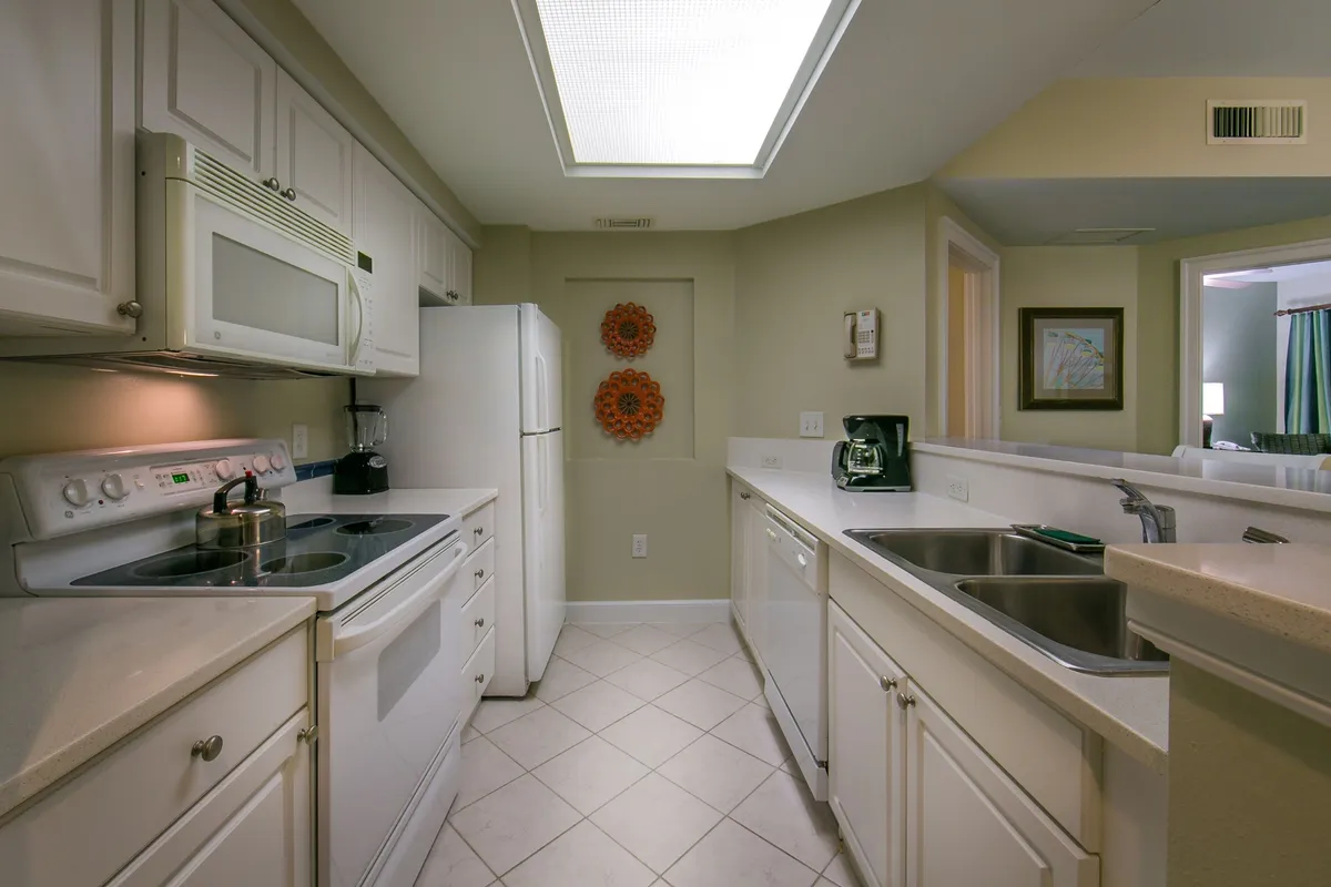 A bright, open living-kitchen area with stainless steel appliances, striking wall art, and a large skylight. The space buzzes with activity—ideal for cooking, casual dining, and family gatherings—with a mood that’s both vibrant and welcoming.