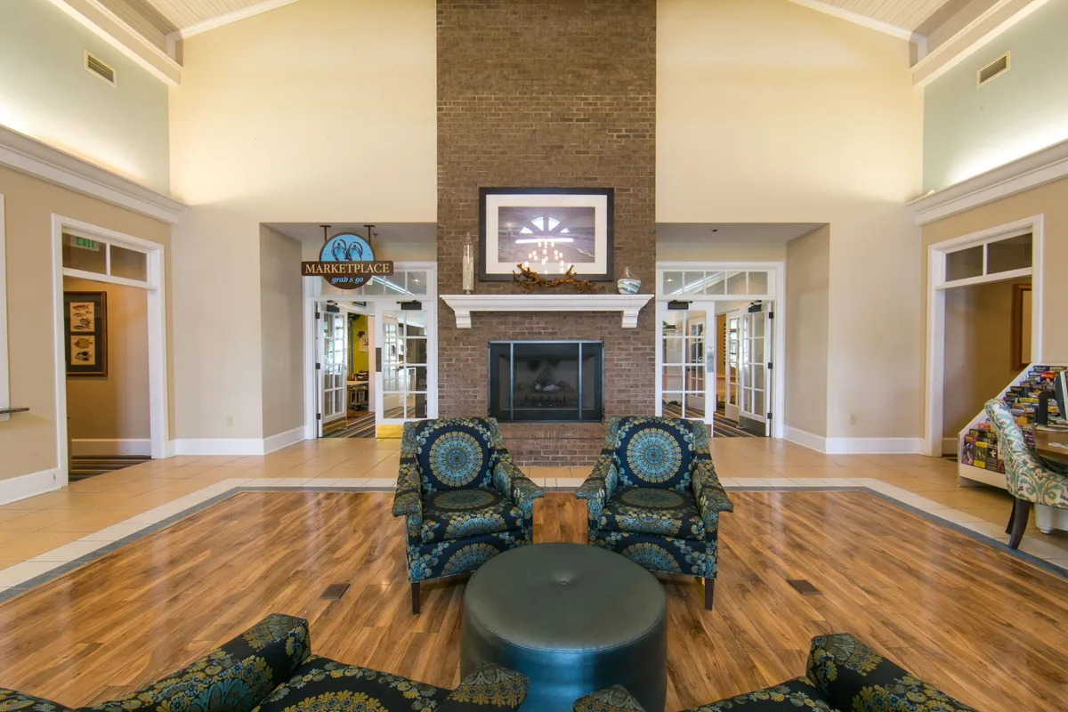 A cozy interior scene centered around a brick fireplace, with a comfortable seating area and a 'Marketplace' sign visible. The inviting furniture and warm ambiance set the stage for relaxed socializing and cozy evenings by the fire.