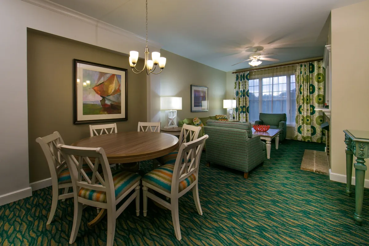This interior image features a welcoming living area with a large sofa, a dining table, colorful curtains, and vibrant artwork. The space is designed for relaxation and togetherness, ideal for family meals, game nights, or simply unwinding after a day's adventures.